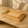 Three nesting rectangular bamboo serving trays with polished golden handles on a light wood table - Trenducts Pakistan