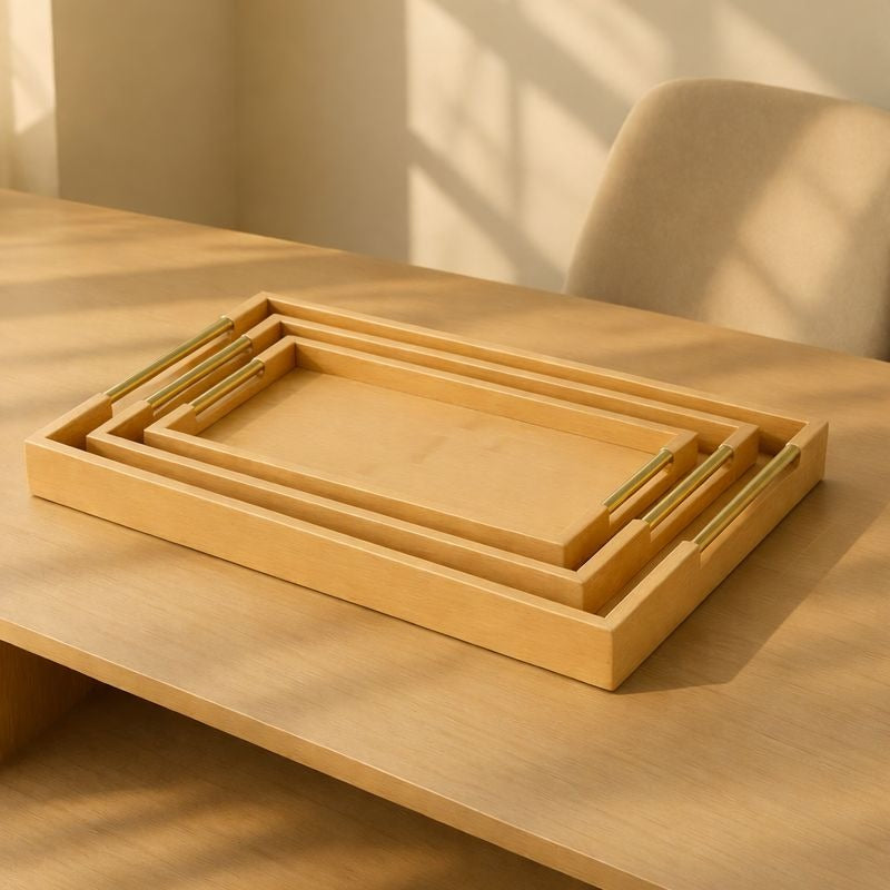 Three nesting rectangular bamboo serving trays with polished golden handles on a light wood table - Trenducts Pakistan