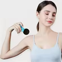 Handheld muscle massager for back pain used by woman relaxing shoulder muscles